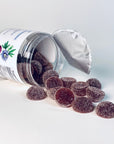 Dark berry gummies spilling from an open jar on a white background, representing nighttime sleep support supplements