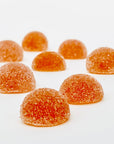 Sugar-coated orange gummies arranged on a white surface