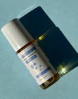 CBD body oil roll-on casting shadow on blue background in direct sunlight.