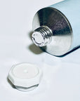 Close-up of sealed aluminum cream tube with white cap removed