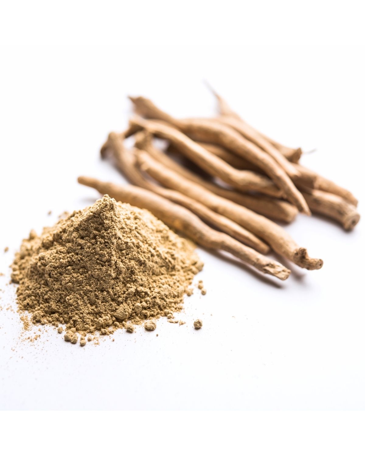 Pile of ashwagandha powder beside whole dried ashwagandha roots on a white background