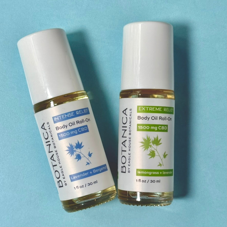Two Botanica CBD body oil roll-on bottles on a blue background, featuring intense and extreme relief formulas