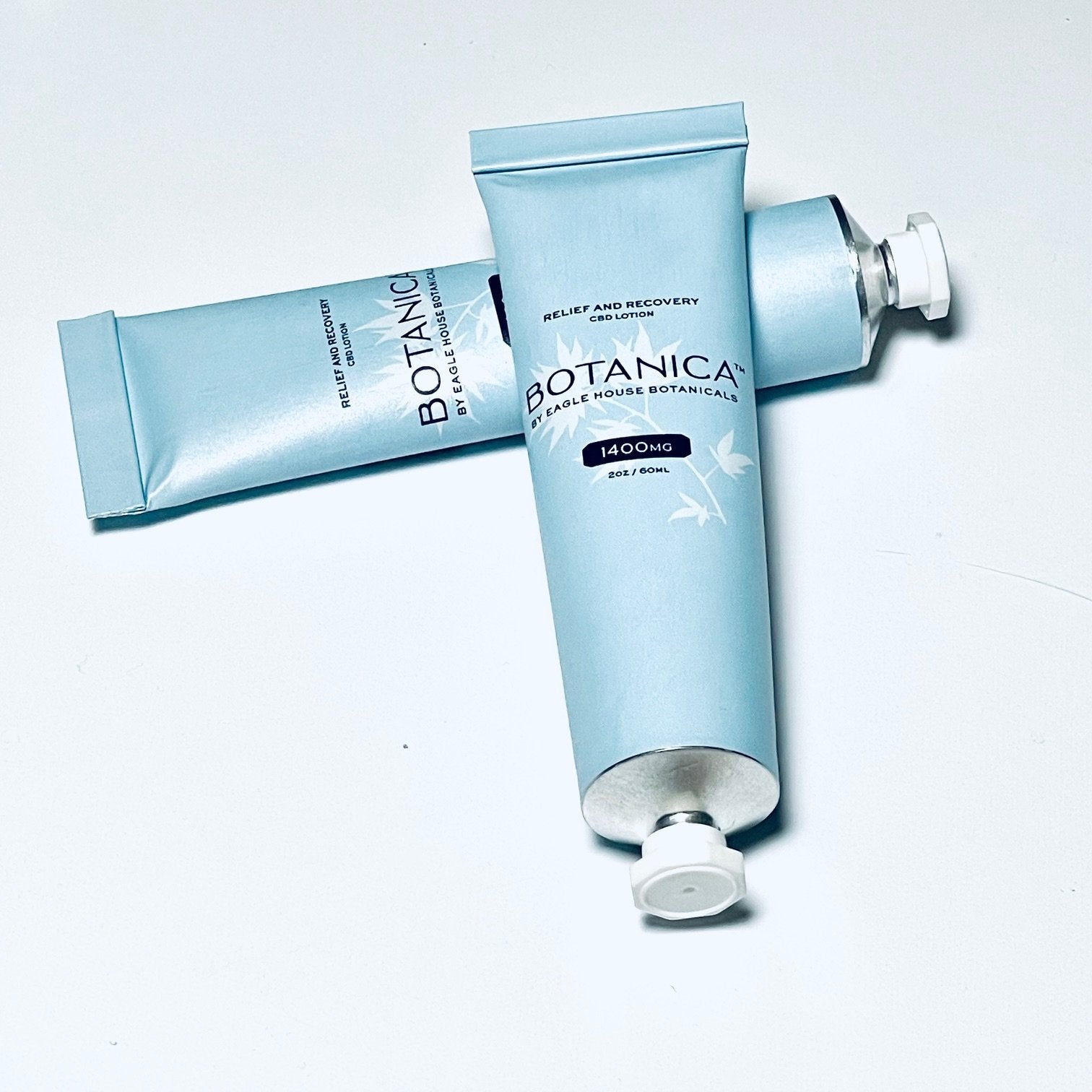 Two blue tubes of Botanica CBD lotion labeled for relief and recovery