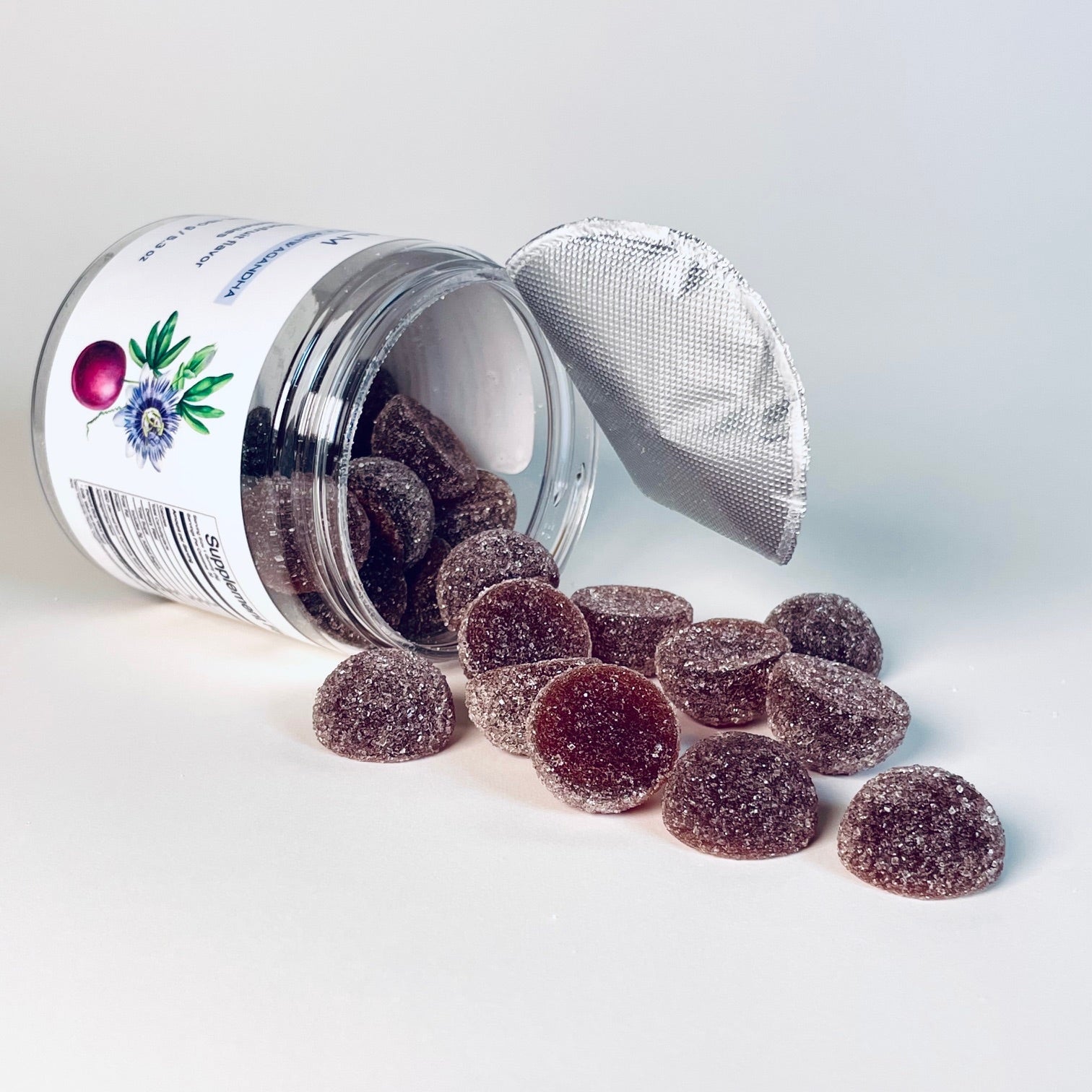 Dark berry gummies spilling from an open jar on a white background, representing nighttime sleep support supplements