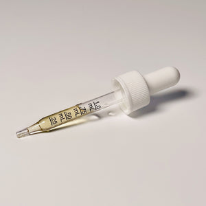 Glass dropper with measurement markings and white cap on white background