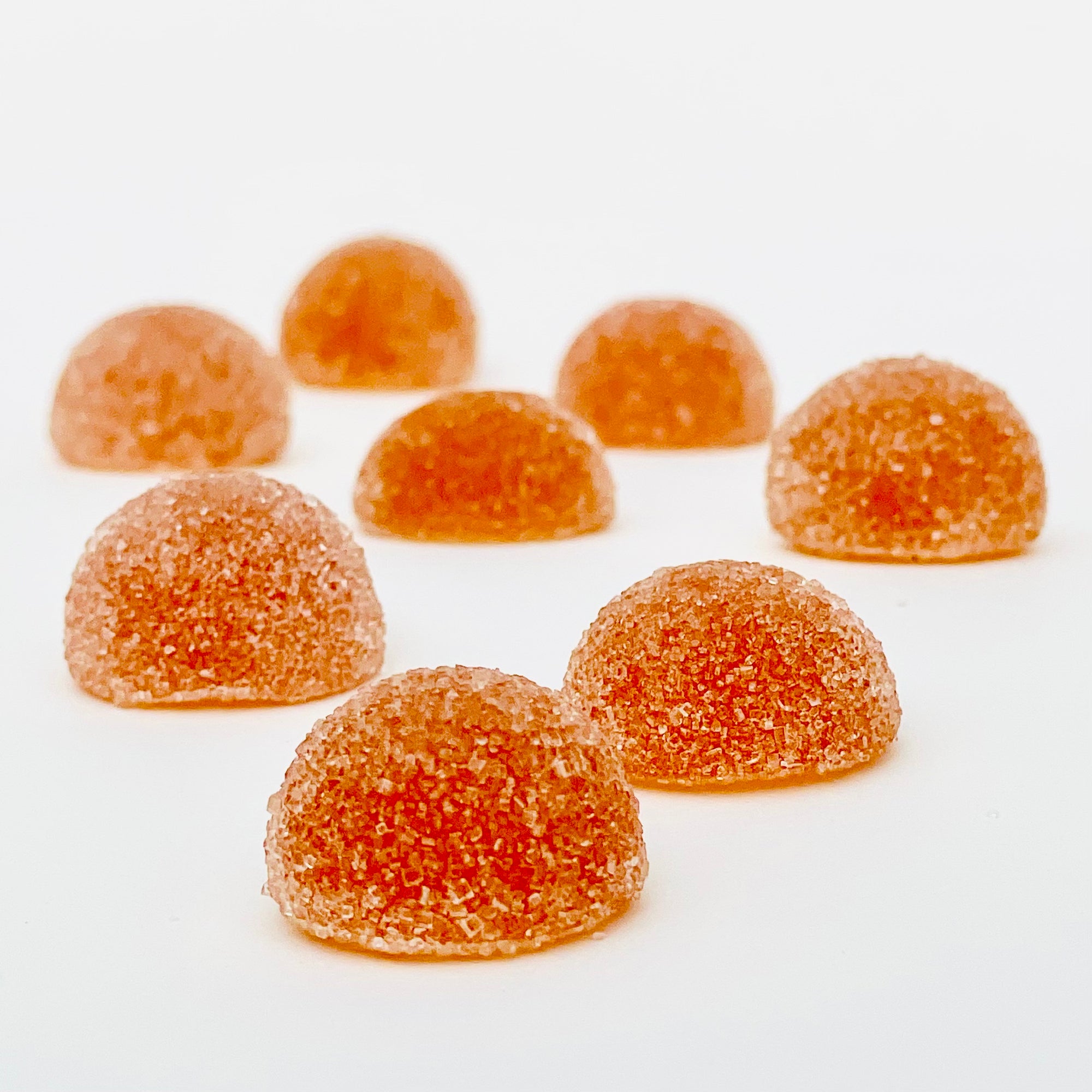 Sugar-coated orange gummies arranged on a white surface