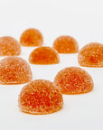 Sugar-coated orange gummies arranged on a white surface