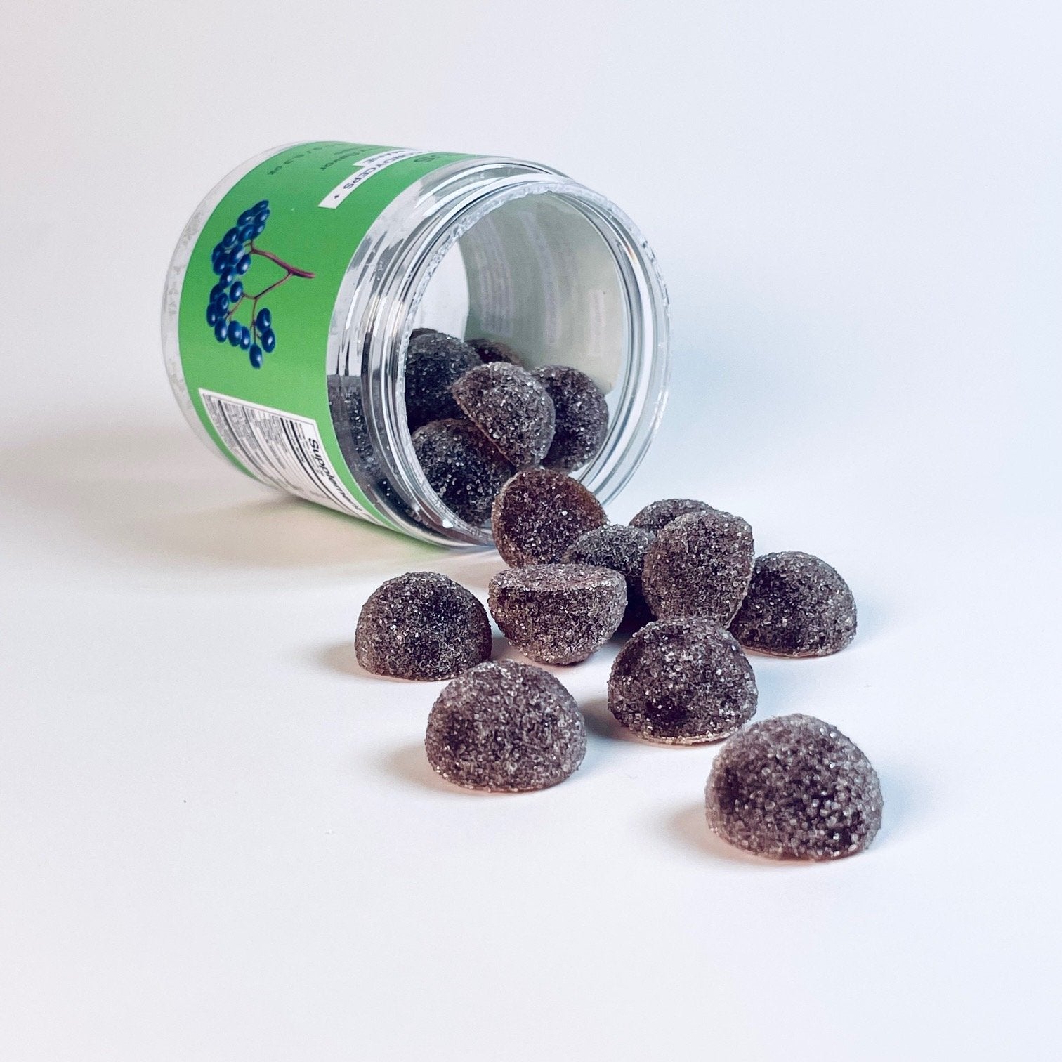 Sugar-coated elderberry gummies spilled from a green-labeled jar