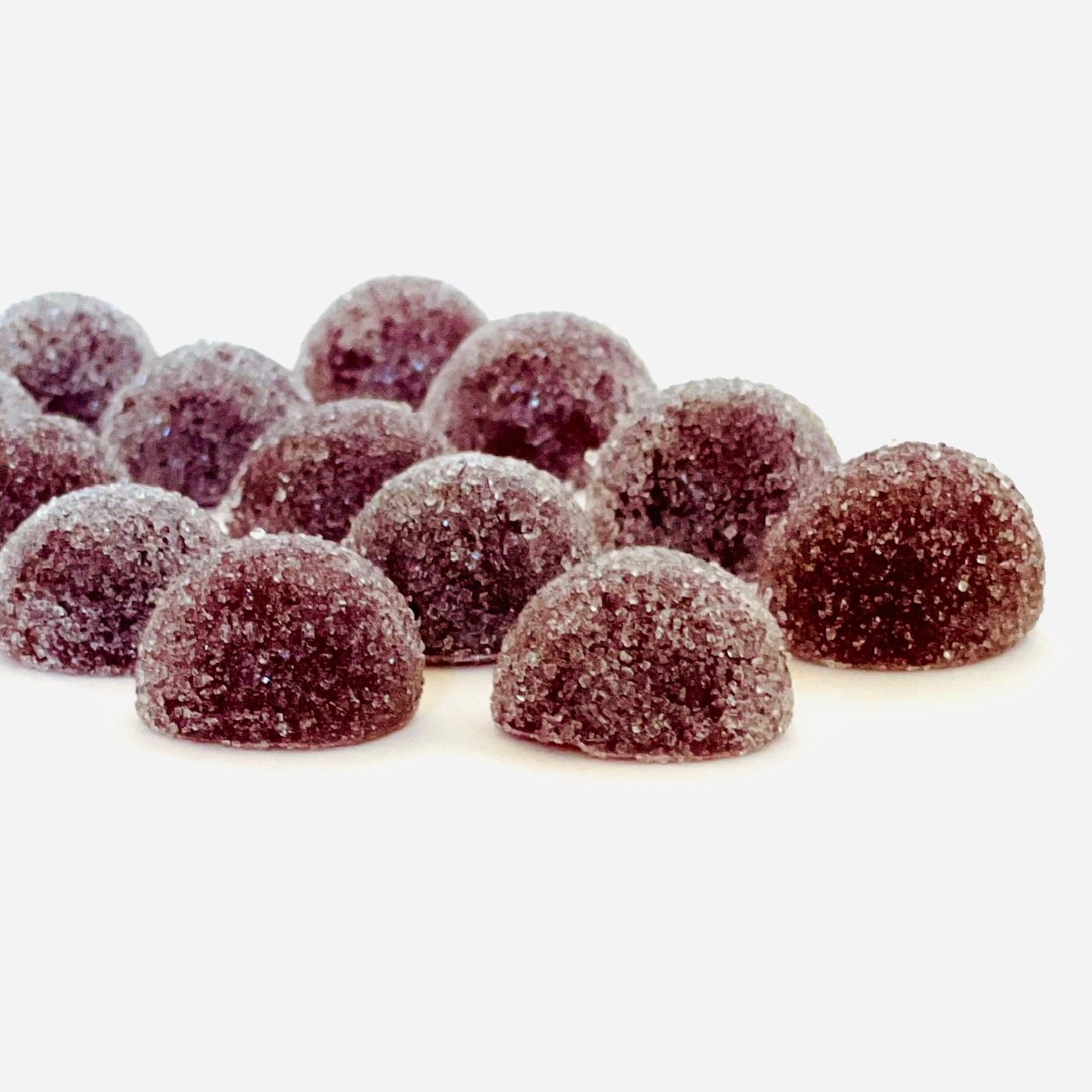 Sugar-coated purple gummies in a half-dome shape on white background