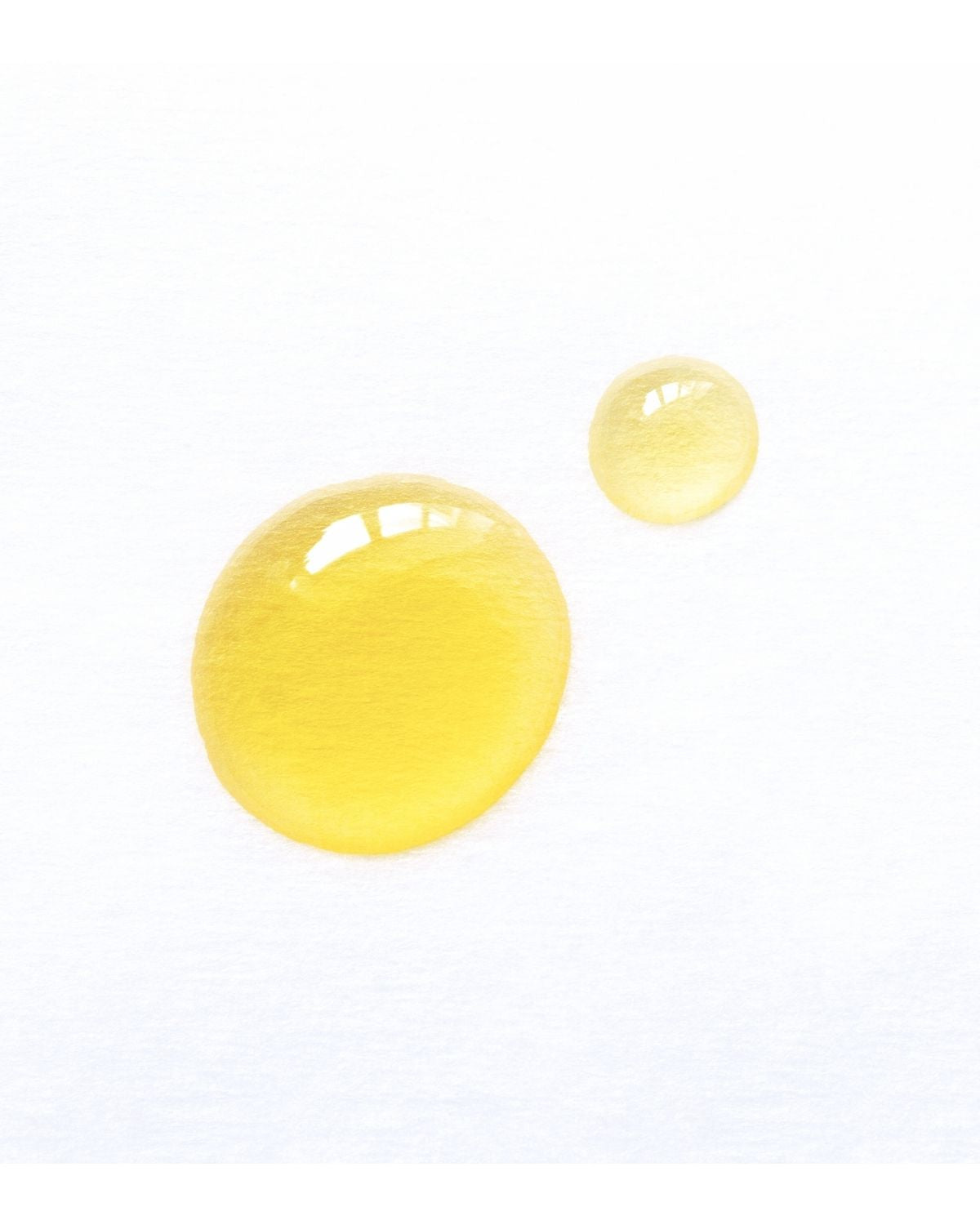 Golden vitamin E oil droplets on a clean white background, showing smooth, glossy texture