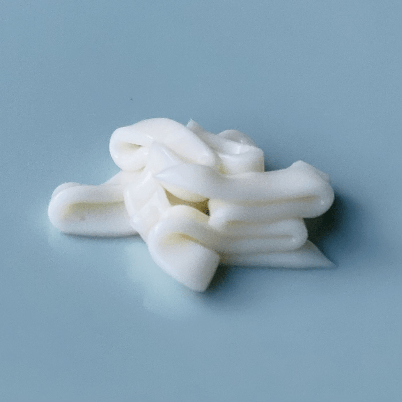 Swirl of white body cream on a smooth blue background