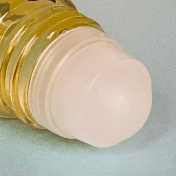 Close-up of a roll-on applicator with golden CBD oil in a glass bottle.